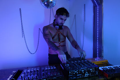 DJ trägt rotes Leder Harness für Herren beim Techno-Set am Mischpult mit Clubbeleuchtung